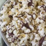 Chocolate Covered popcorn in a white bowl with a green linen off to the side.