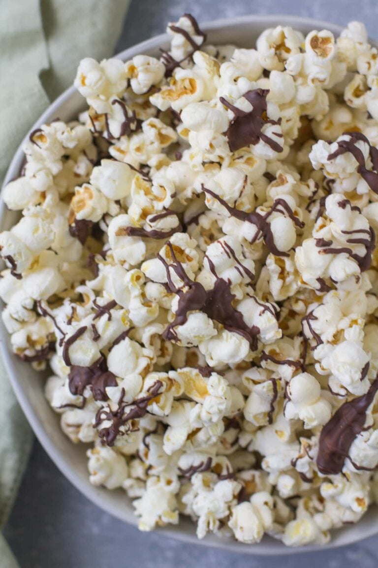 Chocolate Covered popcorn in a white bowl with a green linen off to the side.