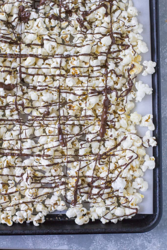 An overhead shot of chocolate covered popcorn cooling on a baking sheet