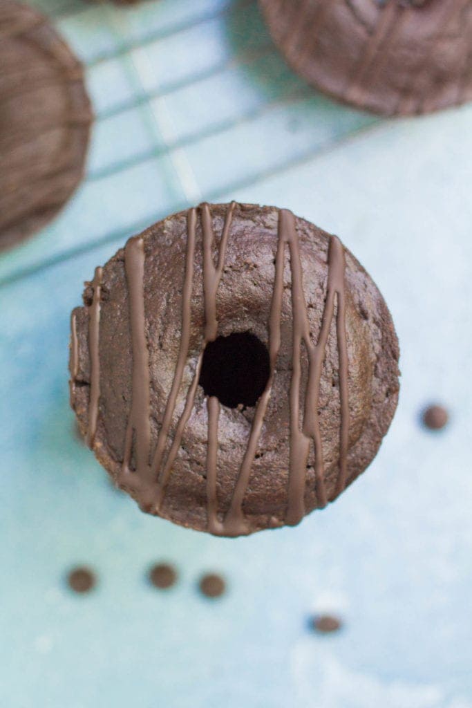 a stack of healthy chocolate donuts with chocolate chips scattered all around the donuts