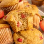 Strawberry Protein Muffins in a pile with a muffin with a bite taken out of it on top.