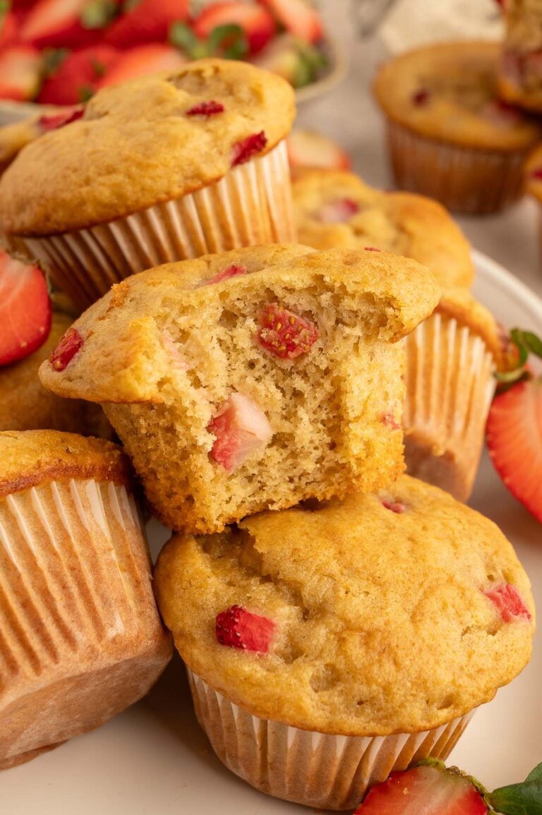 Strawberry Protein Muffins in a pile with a muffin with a bite taken out of it on top.