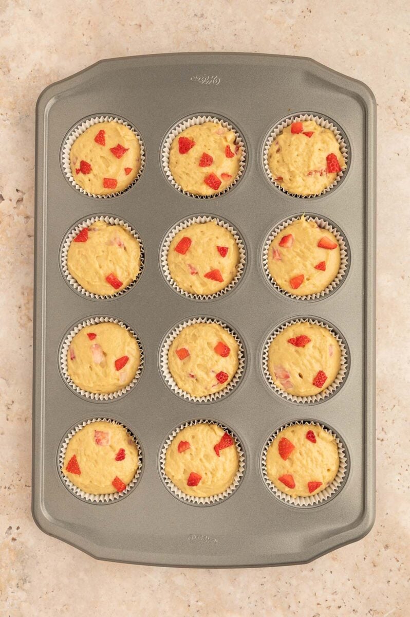 Unbaked strawberry protein muffins in a muffin tin.