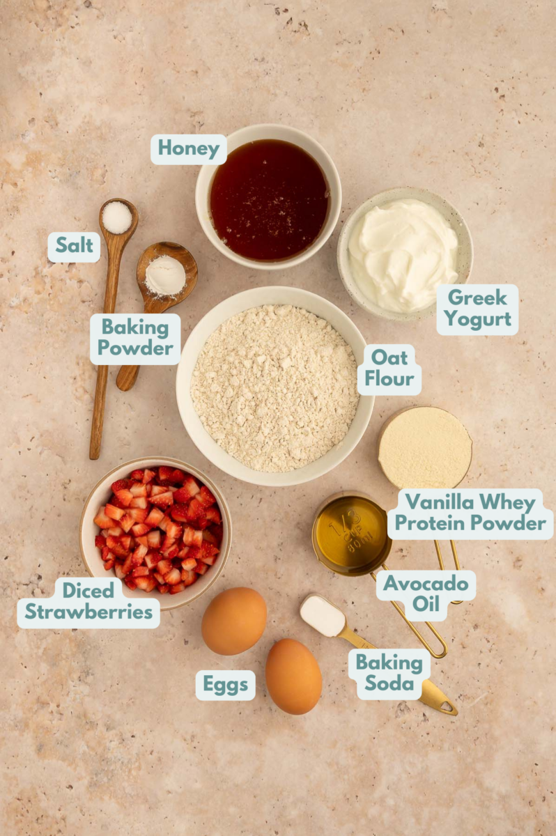 Labeled ingredients for strawberry protein muffins in small bowls.