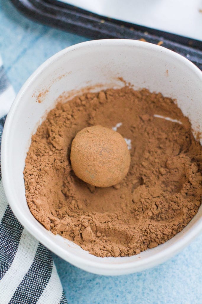 A healthy chocolate truffle being rolled in cocoa powder.