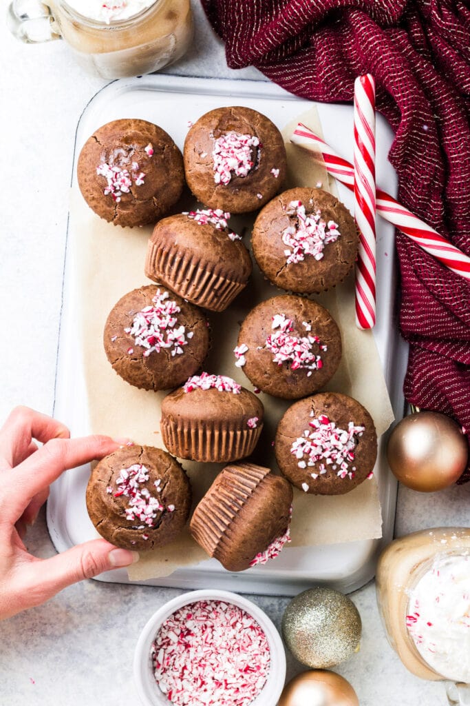 Peppermint Mocha Muffins on a white tray with candy canes and ornaments off to the side.