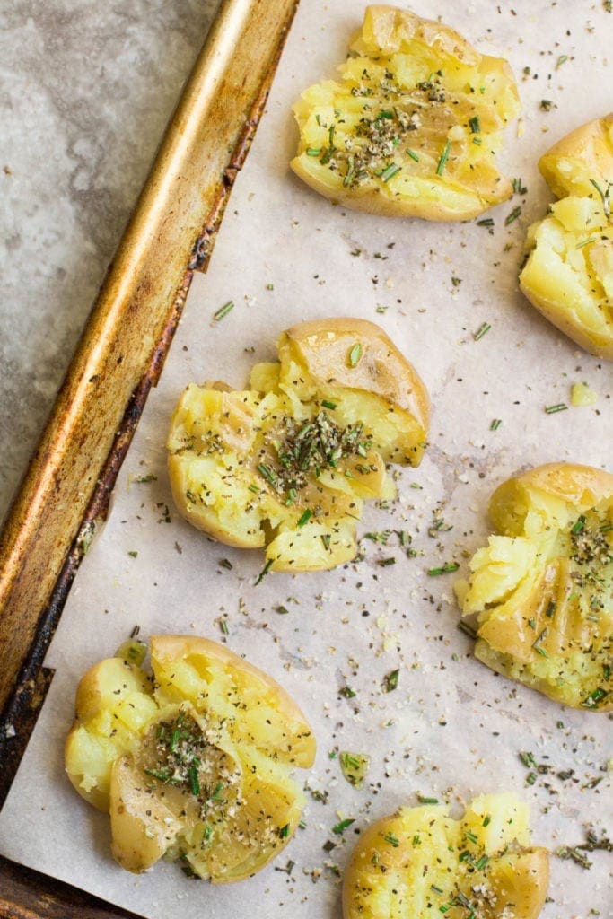 Crispy Rosemary Smashed Potatoes on a parchment lined baking sheet