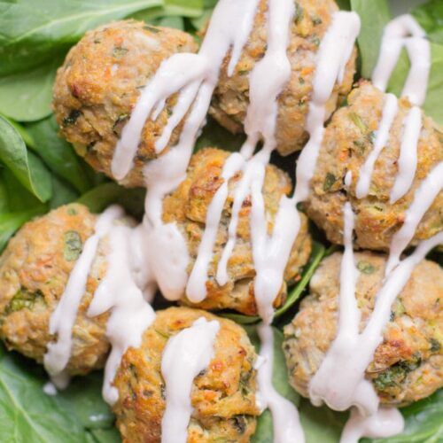 Healthy Buffalo turkey meatballs over a bed of spinach with a greek yogurt drizzle