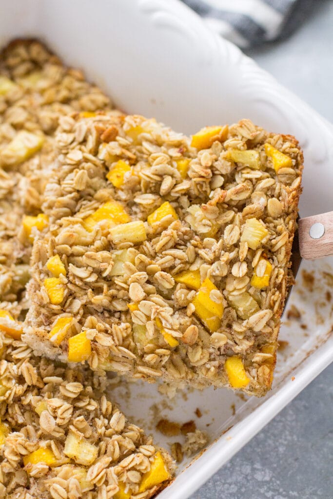 A spatula scooping out a piece of baked oatmeal from the baking dish.
