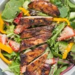 Balsamic grilled chicken on a colorful salad in a white bowl
