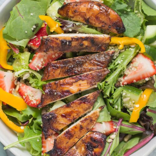 Balsamic grilled chicken on a colorful salad in a white bowl