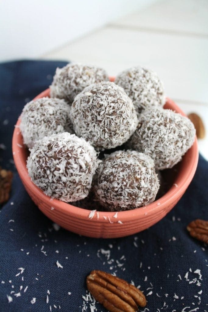 whole30 energy bites in a pink bowl on a white background with a blue linen.