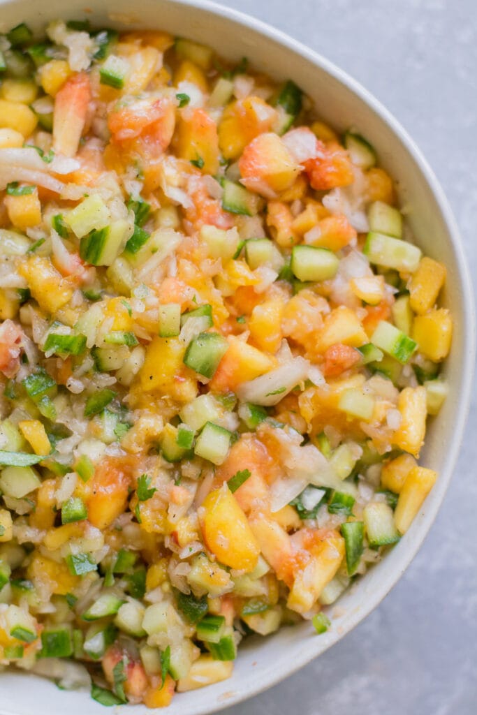 Peach Salsa in a white bowl on a grey background