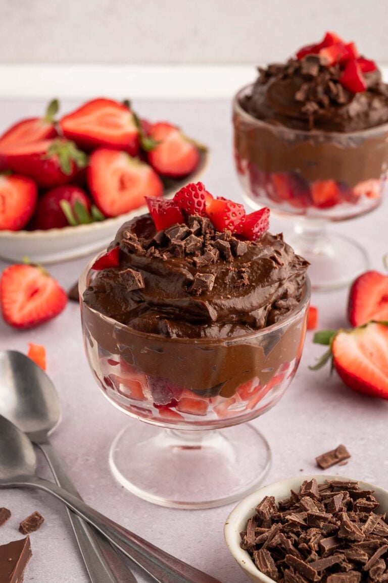 Chocolate Avocado Pudding in a clear serving dish topped with chopped strawberries and more berries in the background.