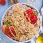 a white bowl filled with egg white oatmeal, topped with strawberries and nut butter