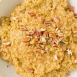 Slow Cooker Steel Cut Oats in a white bowl on a grey background with a blue linen to the side