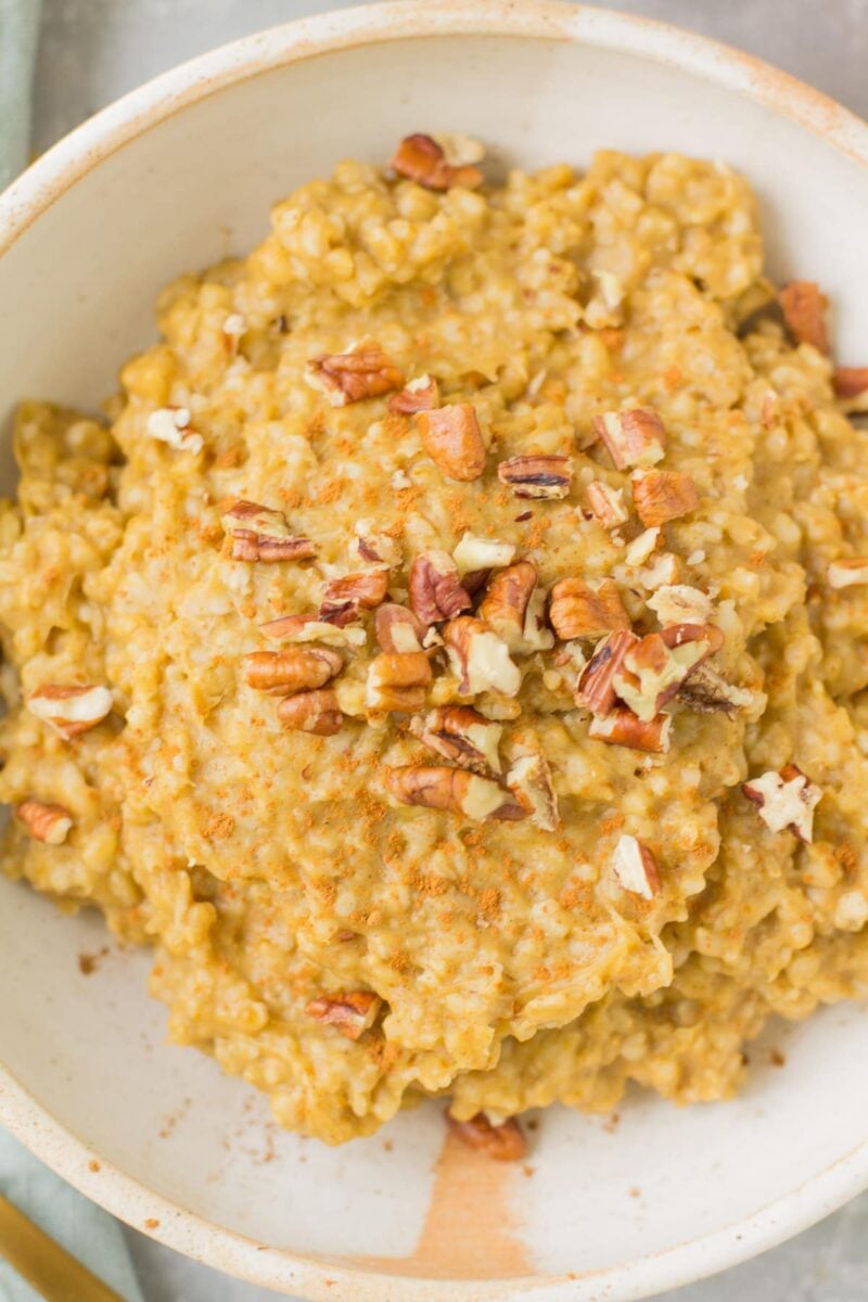 Slow Cooker Steel Cut Oats in a white bowl on a grey background with a blue linen to the side