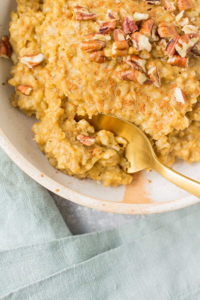 A bowl of slow cooker steel cut oats with a gold spoon taking a bite out of it