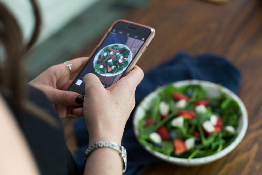 A girl taking a photo of a salad
