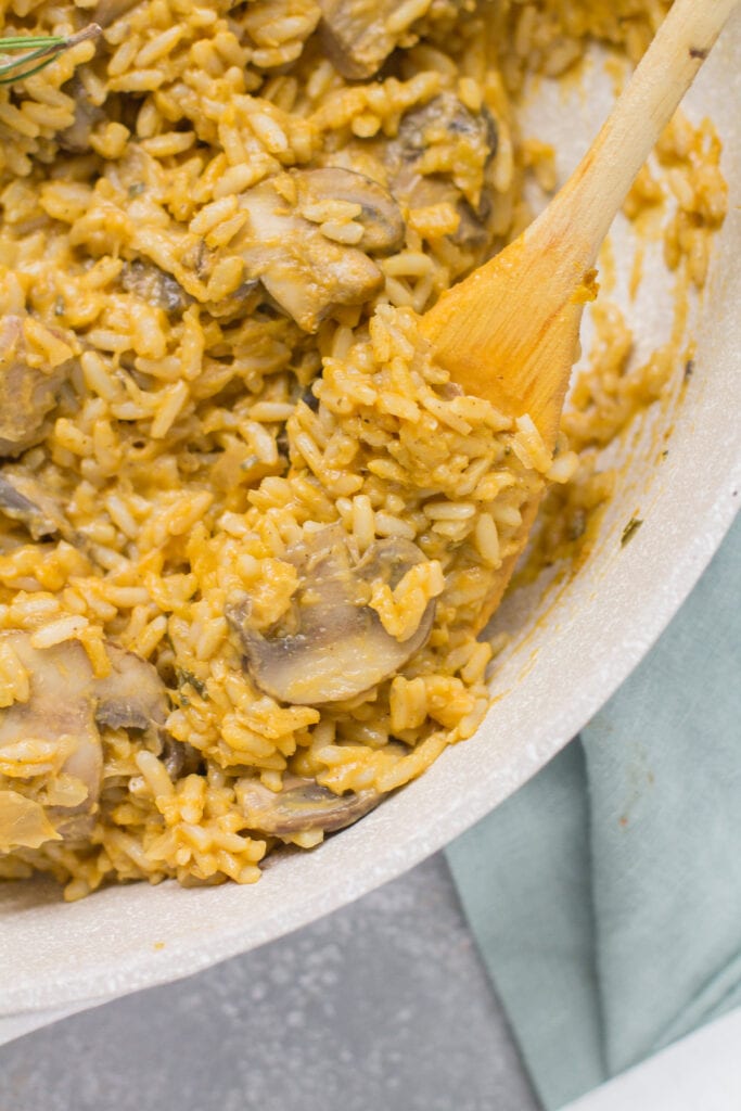 Pumpkin Mushroom Risotto being stirred in a white pot