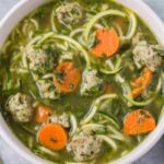 Healthy Italian Wedding Soup in a white bowl on a grey background with a linen off to the right side.