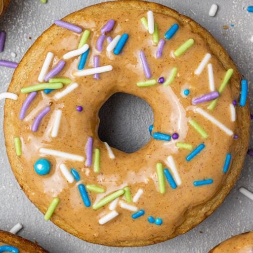A healthy protein donut, baked and decorated with nut butter glaze and colorful jimmies.