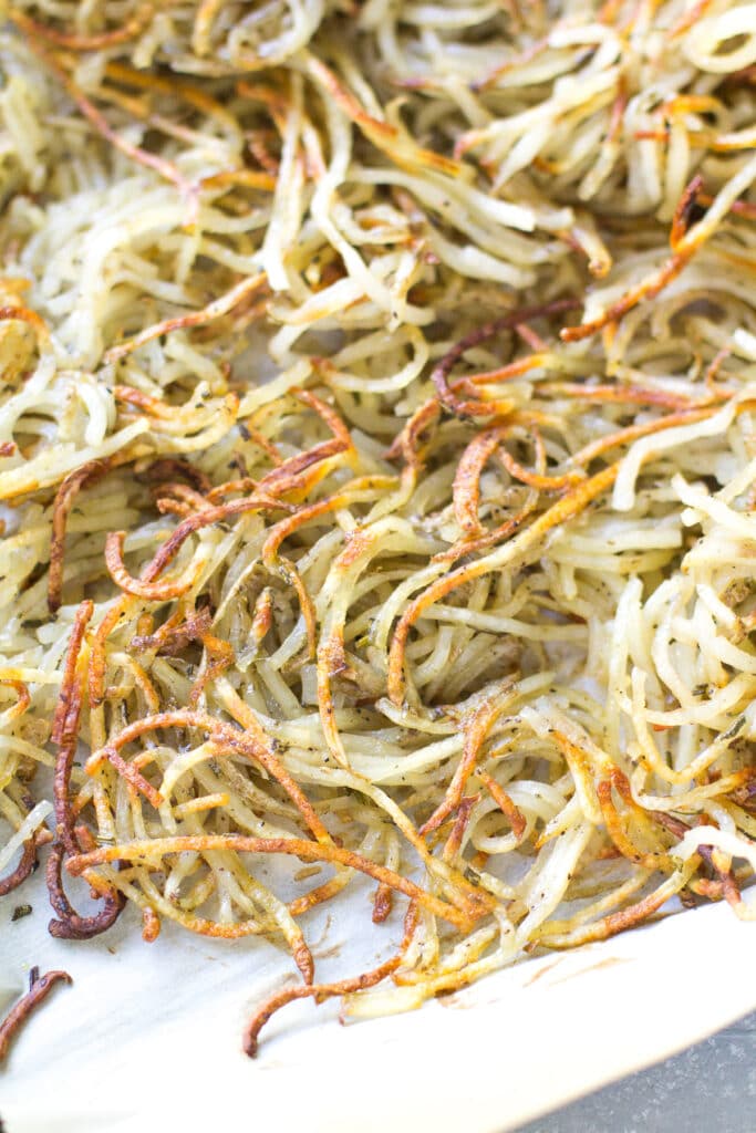 A sheet pan filled with spiralized potatoes ultra crispy and golden brown