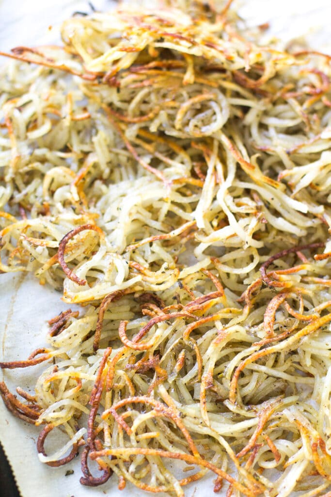 Spiralized crispy potatoes on a parchment lined sheet