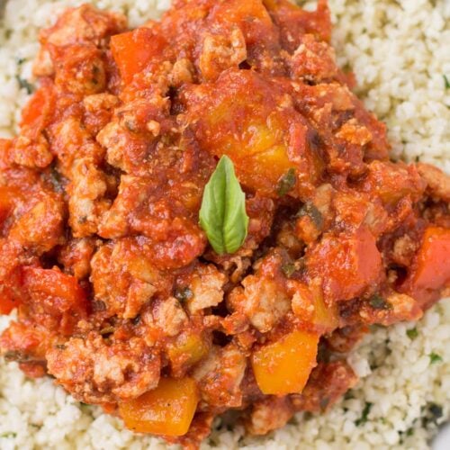 A close up of Healthy Unstuffed Peppers in a white bowl. Ground meat + peppers in a sauce over cauliflower rice.