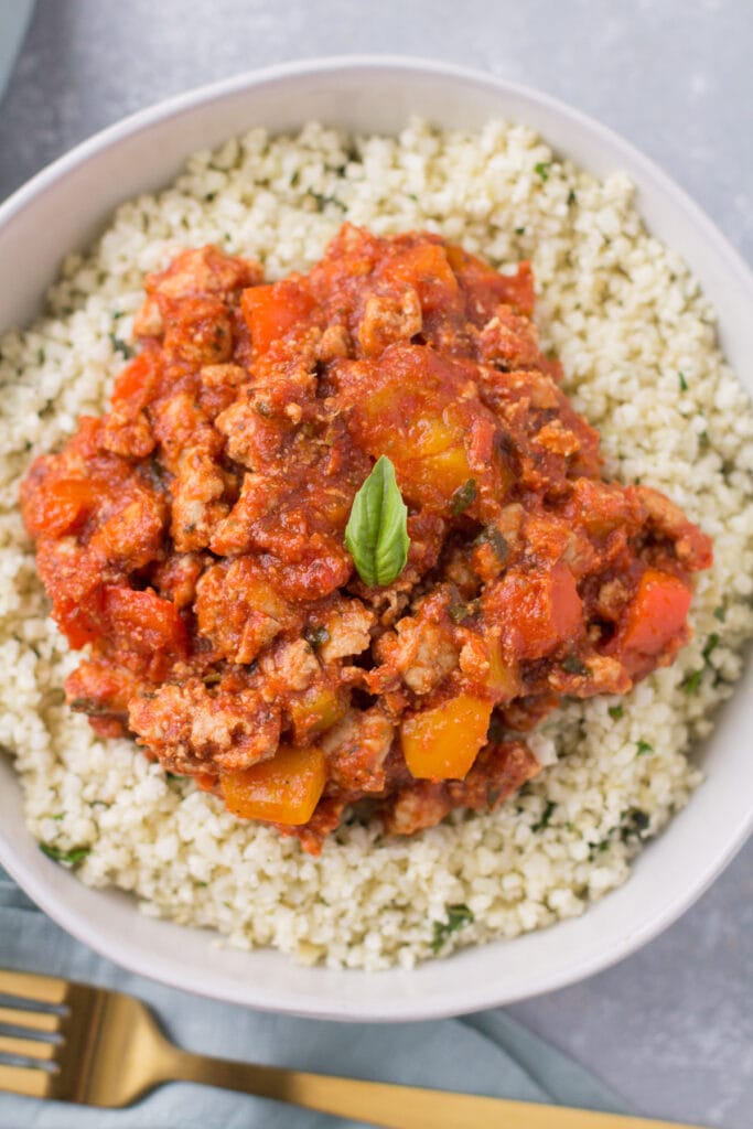An overhead shot of Healthy Unstuffed Peppers in a white bowl. A big bowl of cauliflower rice + meat + veggies