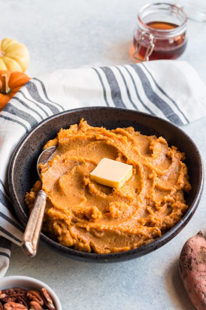 A close up image of paleo sweet potatoes mashed in a black bowl