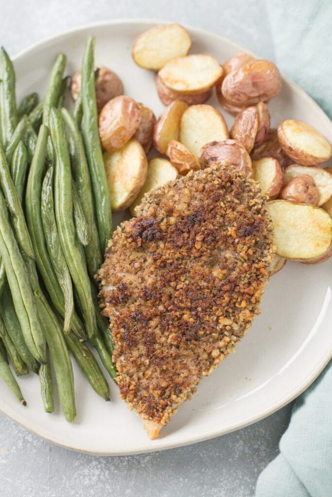 whole30 Pecan Crusted Chicken on a plate with potatoes and green beans