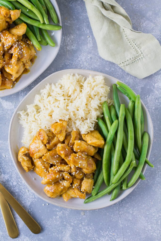 A close up of healthy orange chicken on a white dish on a great background