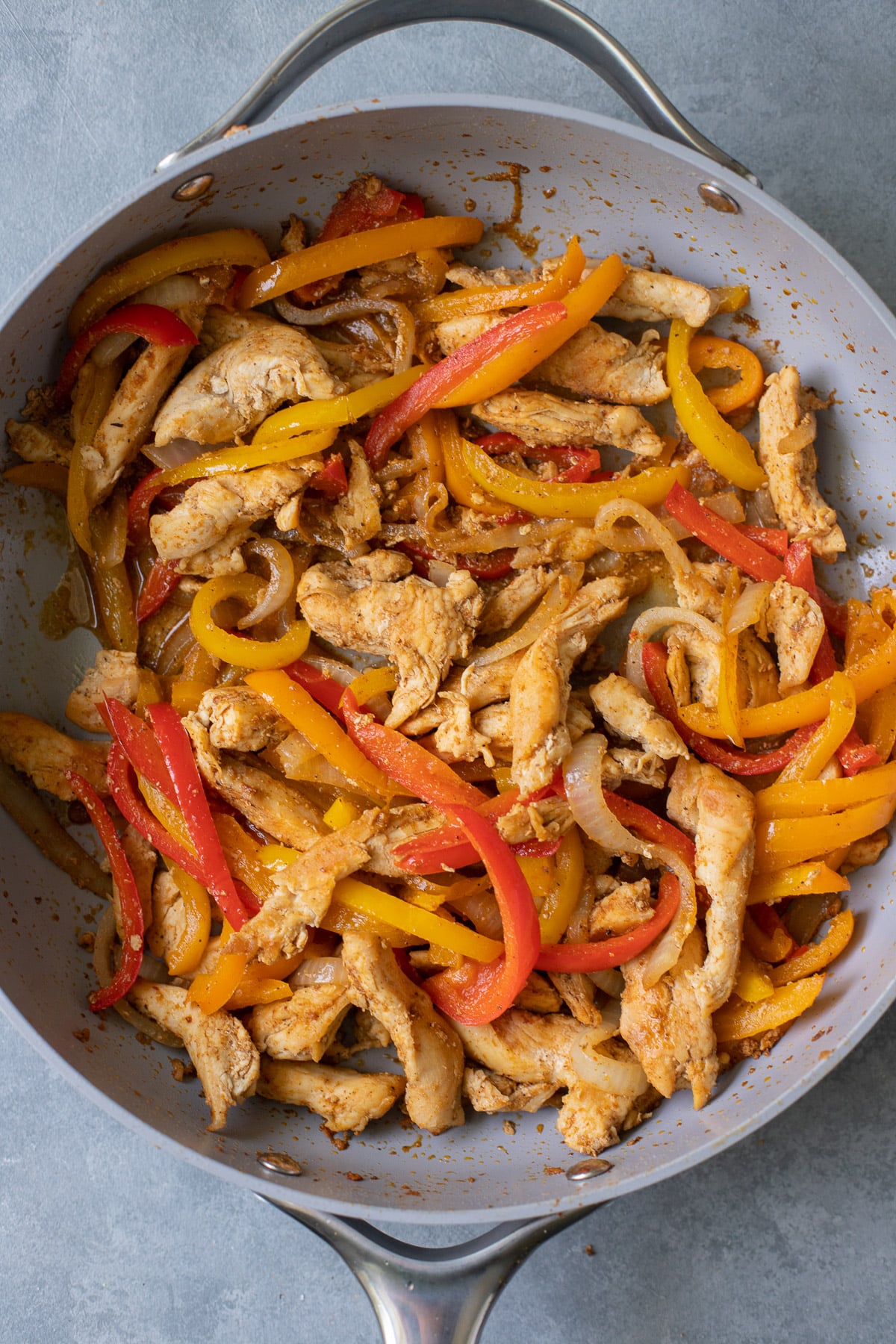 A pan of healthy chicken fajitas on a grey background