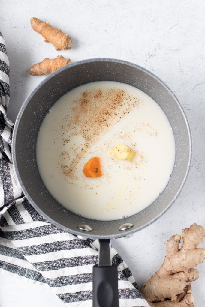 A pan with turmeric latte ingredients in it being heated up to show How to Make a Turmeric Latte