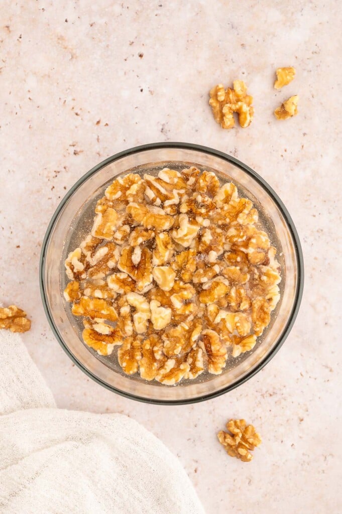 An overhead shot of a bowl of walnuts that have been soaking in water. 
