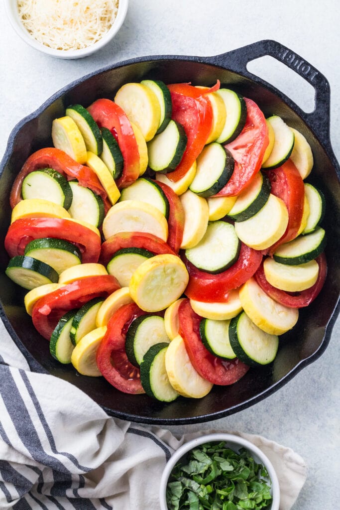 Zucchini, squash and tomatoes in a cast iron skillet before baking