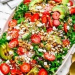A large white bowl with strawberry goat cheese salad on a white background