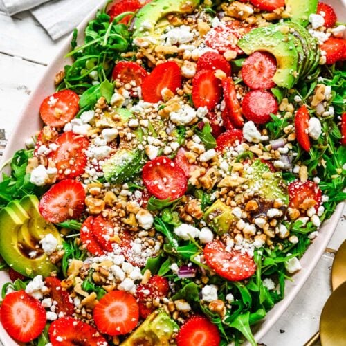 A large white bowl with strawberry goat cheese salad on a white background