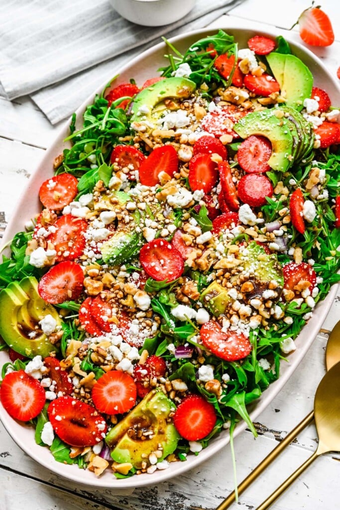A large white bowl with strawberry goat cheese salad on a white background