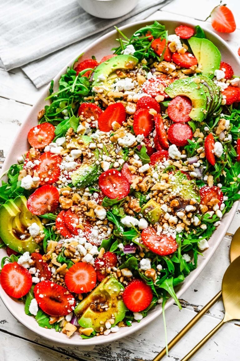 A large white bowl with strawberry goat cheese salad on a white background