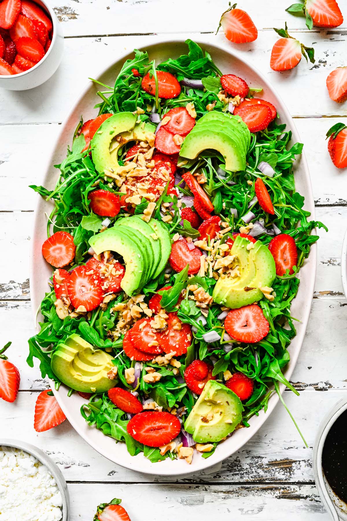 A large white bowl with strawberry goat cheese salad on a white background
