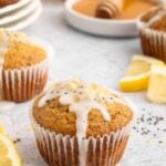 Healthy Lemon Chia Seed Muffin topped with a glaze with more muffins and lemon slices in the background.