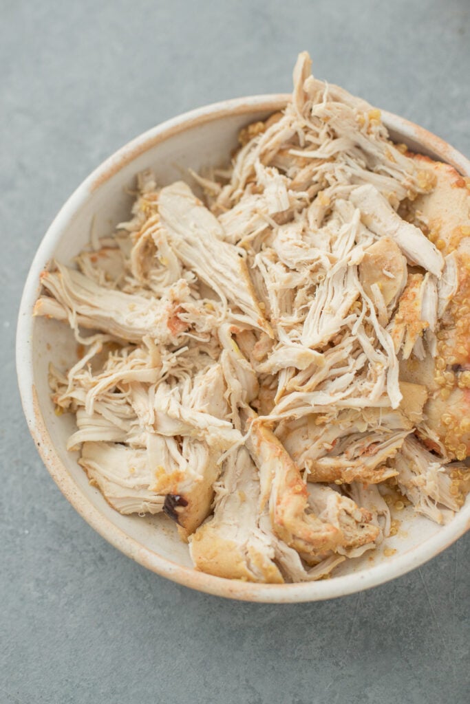 A bowl of shredded chicken on a grey background