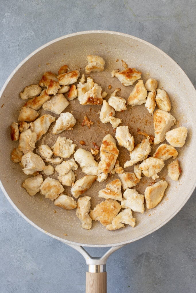 Chicken breasts being browned in a grey pan Pesto Chicken Pasta