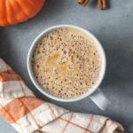 A close up of a pumpkin spice latte on a grey background