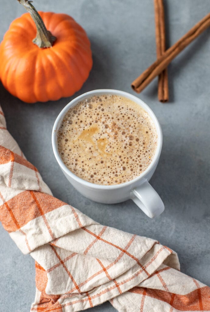 Easy Vegan Paleo Pumpkin Spice Latte in a grey mug with a plaid linen and pumpkin in the background.