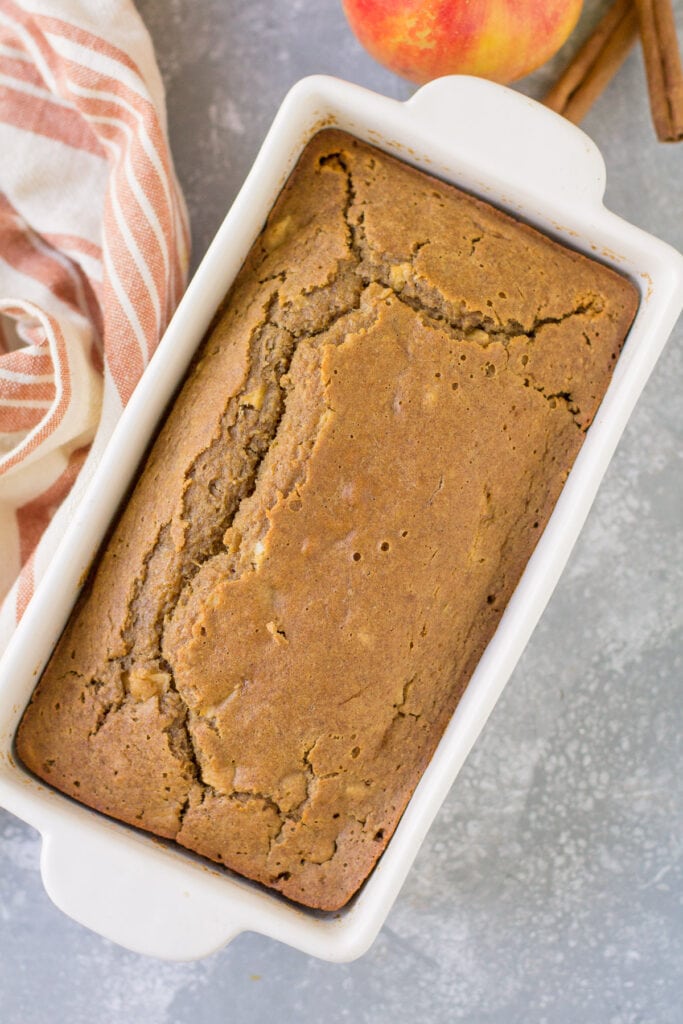 Apple cider bread in a white baking loaf pan on a grey background