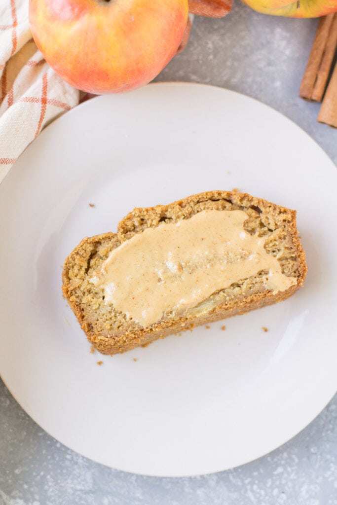 A slice of apple cider bread with nut butter slathered on top.