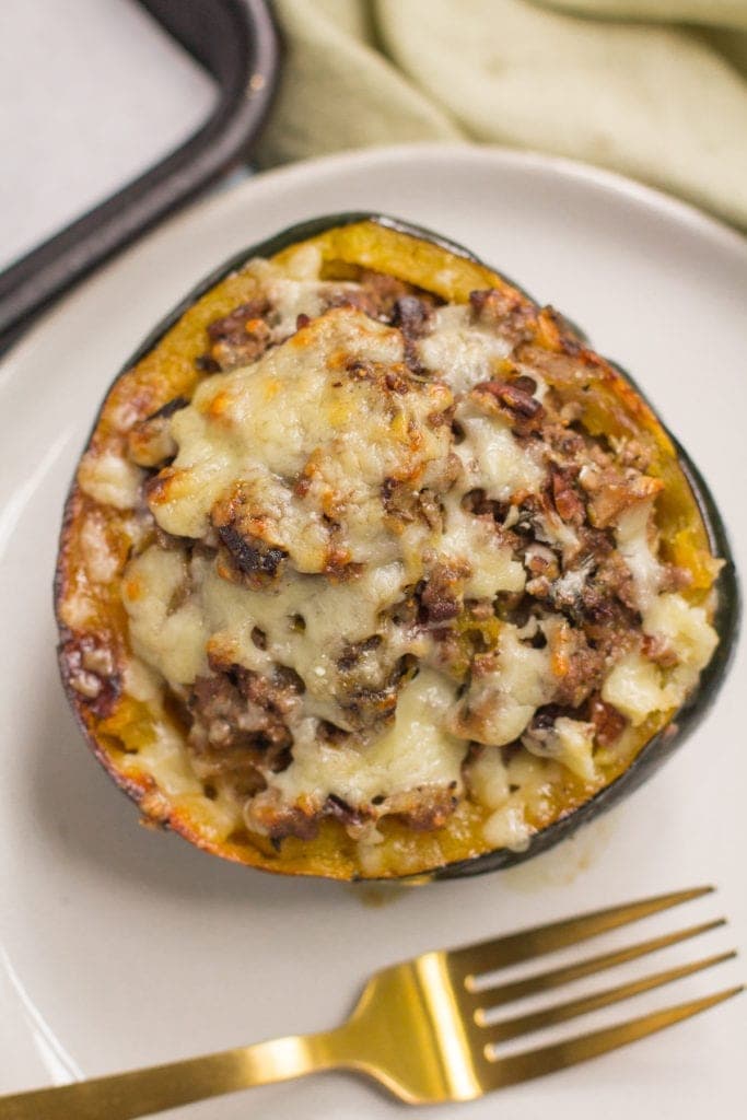 Beef Stuffed Acorn Squash with a gold fork off to the side on a white plate.